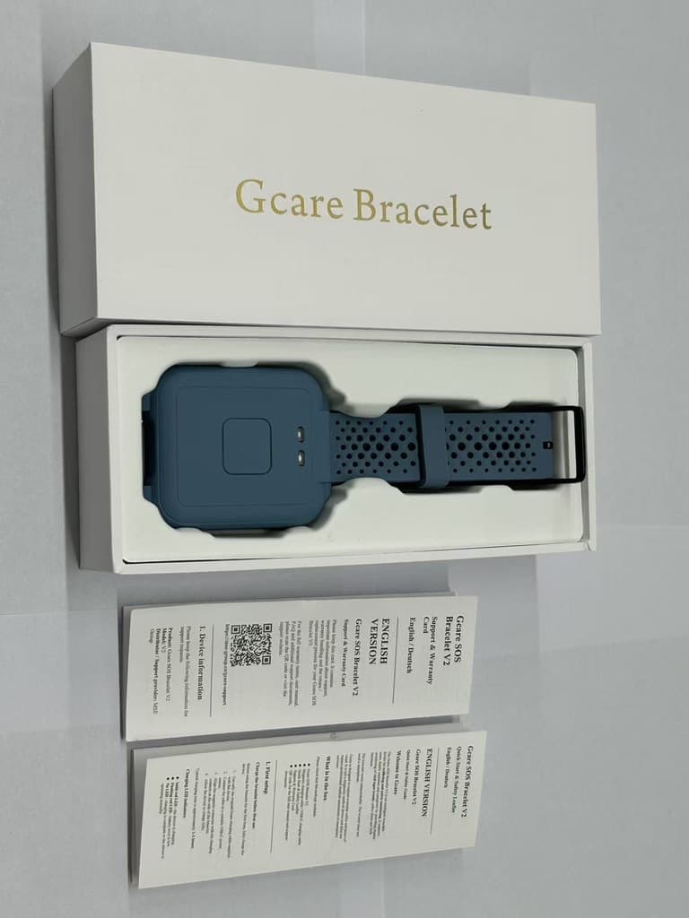 Das GCARE Armband in der geöffneten Originalverpackung, mit gedruckter Kurzanleitung und Support- und Garantiekarte
